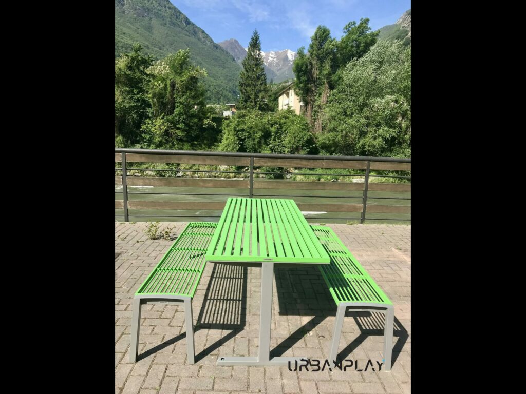 Tavolo con due panche verdi nell’area Liéron di Bard con montagne sullo sfondo