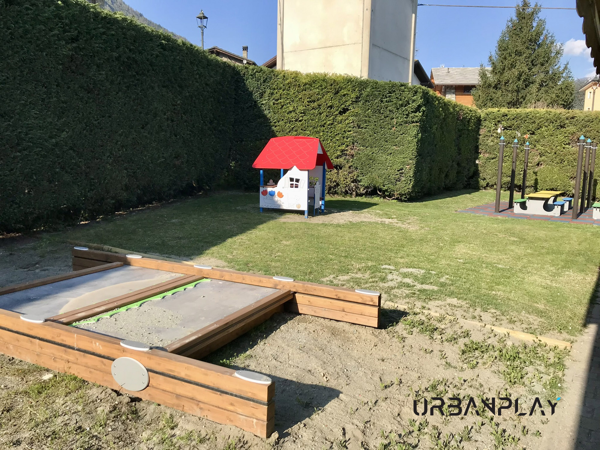 Area giochi scuola materna Pollein con area sabbia, casetta e tavoli nel giardino