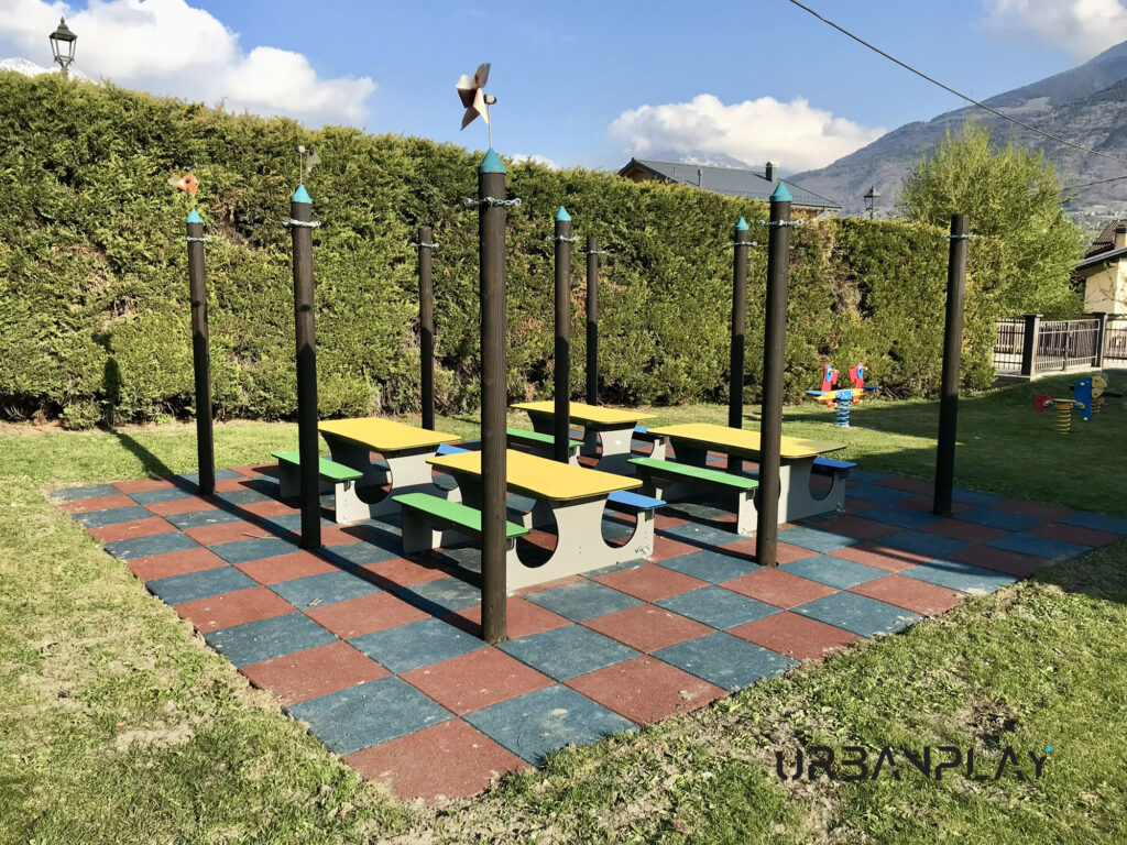 Tavoli con panche su pavimentazione in gomma nell’area esterna della scuola di Pollein