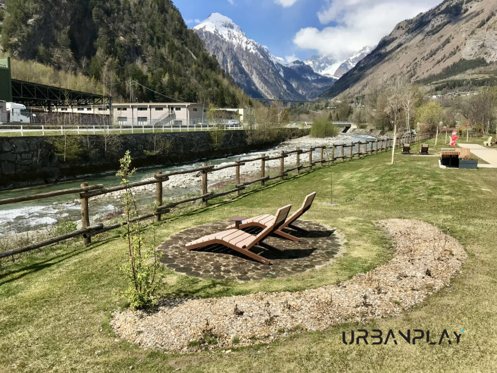 Chaise longue nel verde con corso d’acqua e montagne sullo sfondo a Morgex
