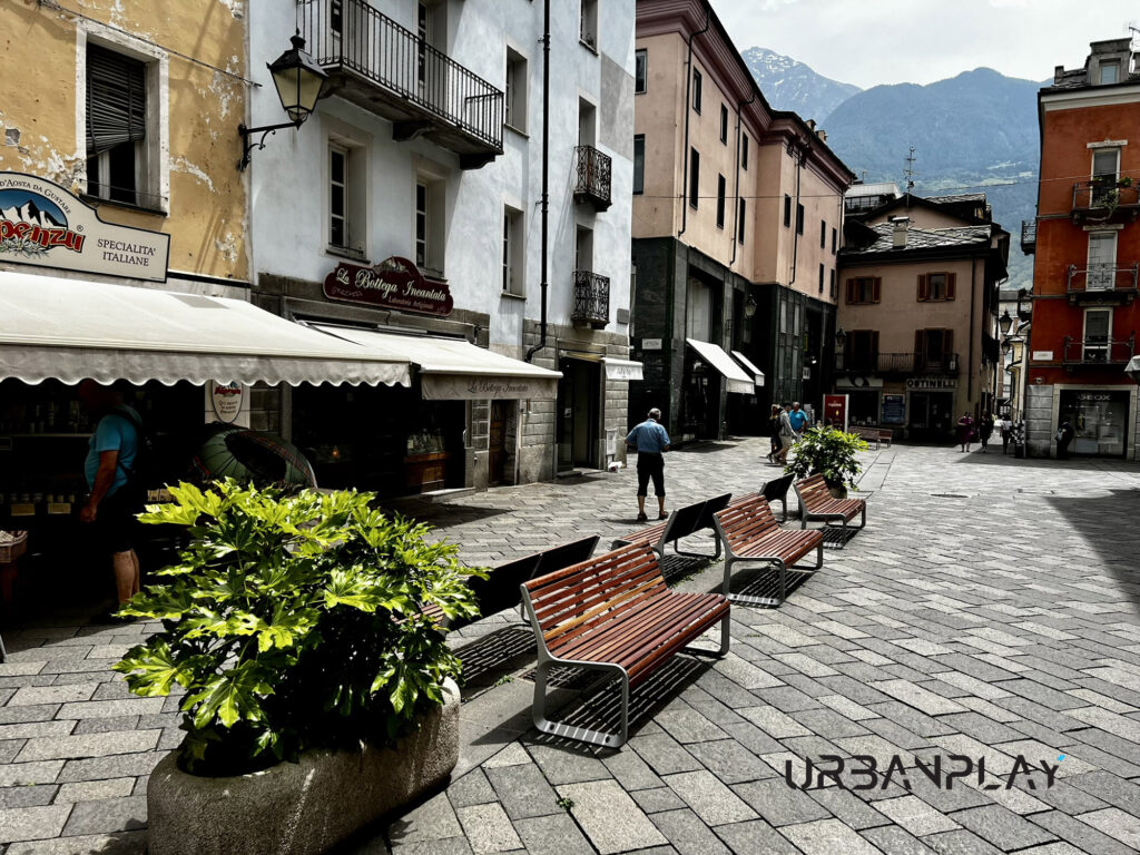 Panchina urbana in legno e metallo posizionata accanto a una fioriera ad Aosta