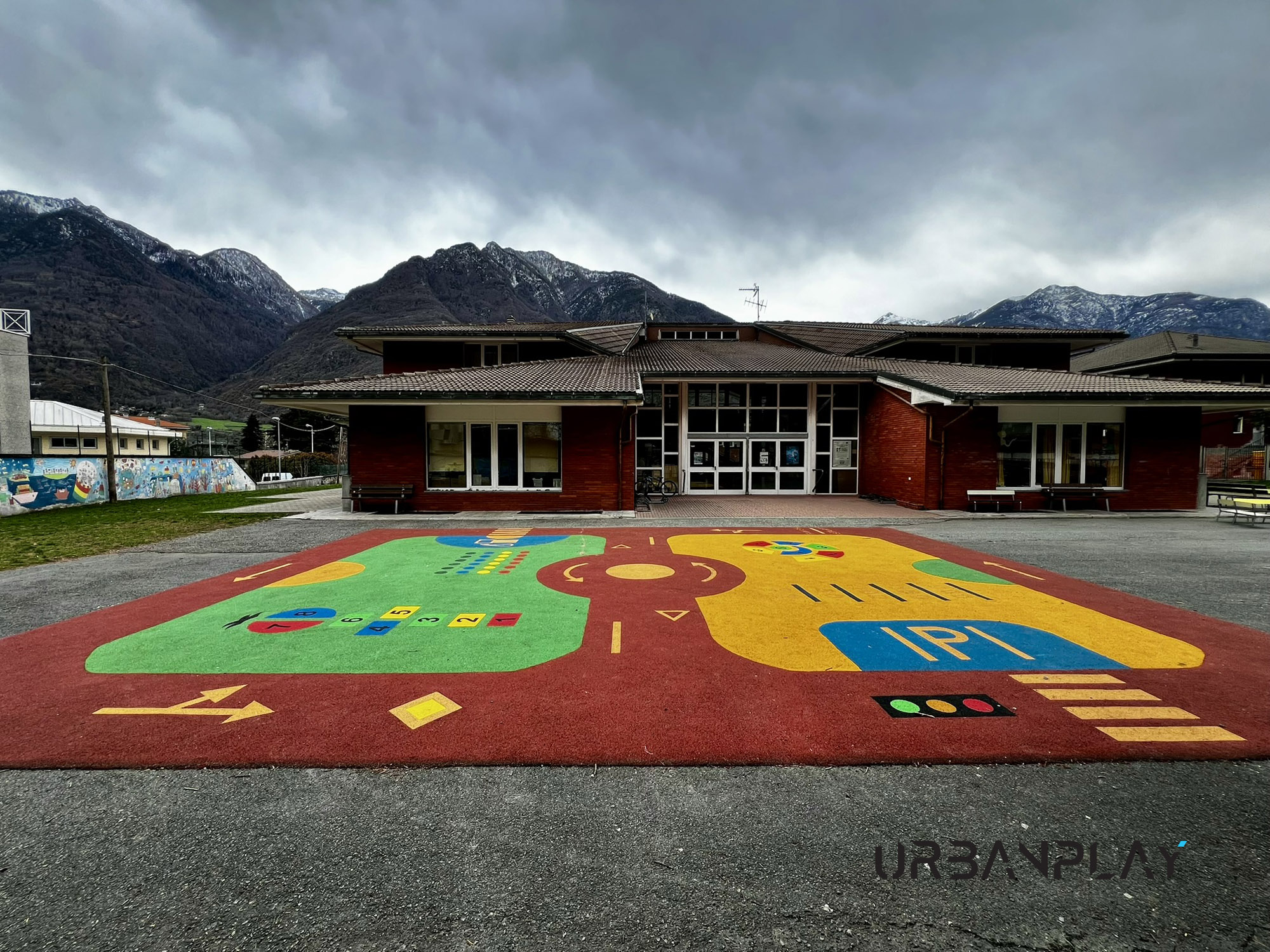 Area gioco scolastica a Verrès con superficie ludica colorata nel cortile della scuola