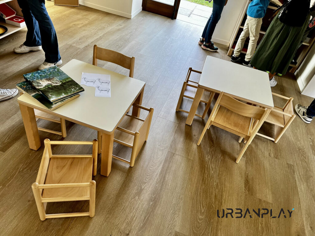 Tavoli e sedute in legno per attività educative nello spazio interno di Cascina Oremo