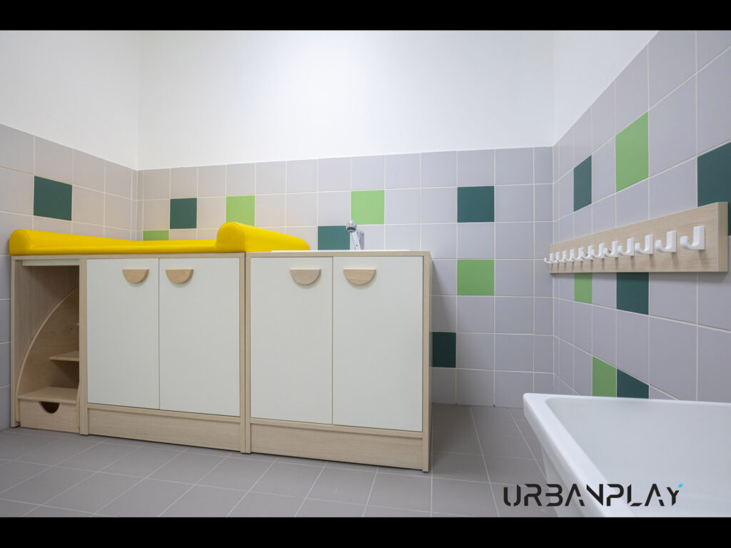 Zona cambio con fasciatoi, lavabo, mobili contenitore e appendiabiti a parete