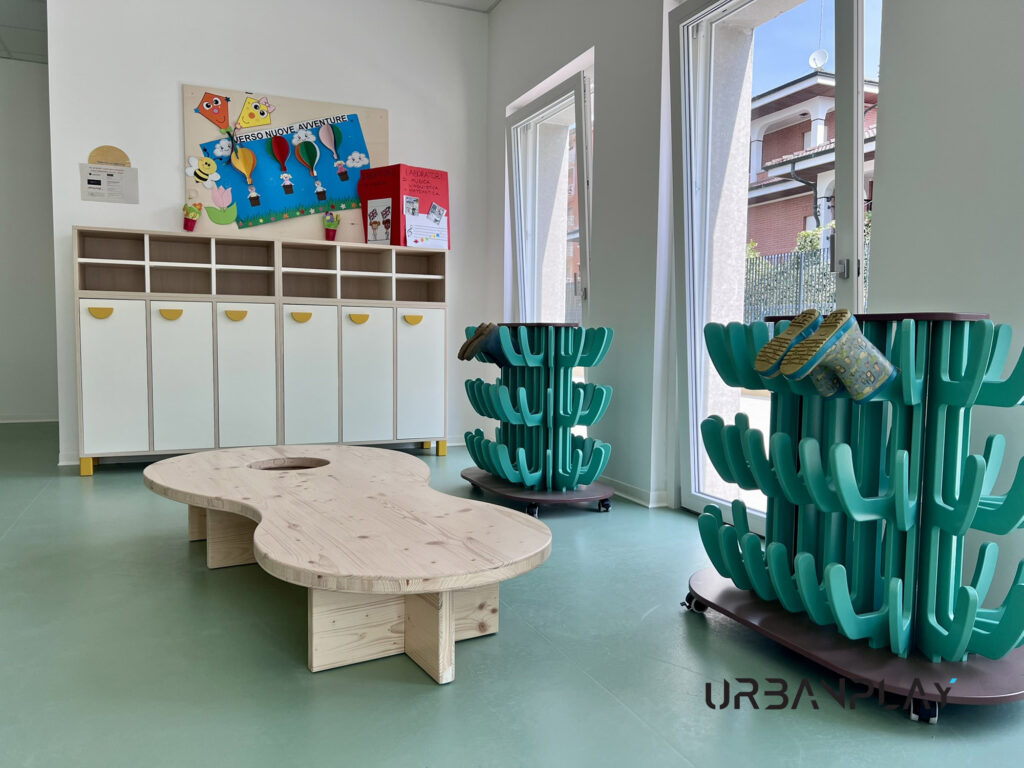 Atelier con tavolo sagomato in legno, espositori mobili e contenitori bassi