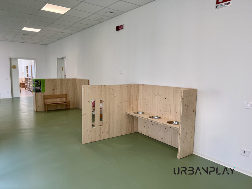 Spazio gioco con struttura in legno naturale, pannelli divisori e ciotole sensoriali