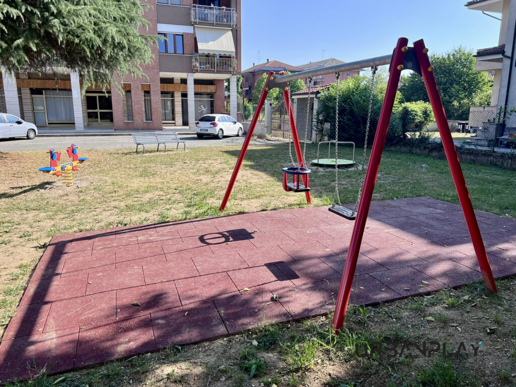 Altalena con pavimentazione antitrauma e attrezzature ludiche nello spazio verde comunale