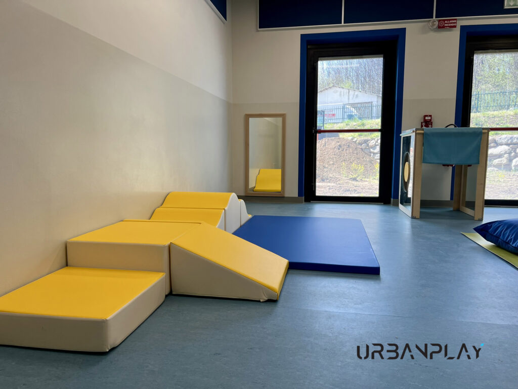 Area morbida con moduli psicomotori, tappeto e specchio nel nuovo asilo nido di Val di Chy